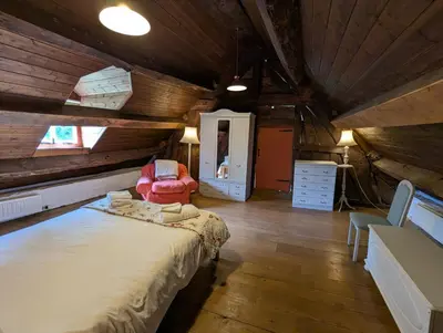 a bedroom with a bed and a chair in a attic at Longhouse - Hen Dy in Rhayader