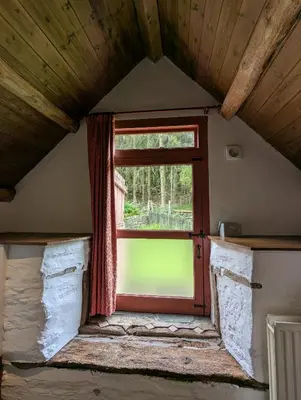 a window in a room with a wooden ceiling at Longhouse - Hen Dy in Rhayader