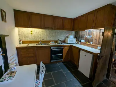 a small kitchen with wooden cabinets and a sink at Longhouse - Hen Dy in Rhayader