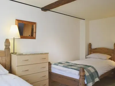 a bedroom with two beds and a dresser and a mirror at Stable Cottage in Oswestry