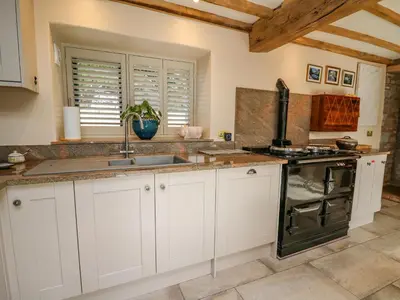 a kitchen with white cabinets and a sink and an oven at Pen Bont Home Farm in Brecon