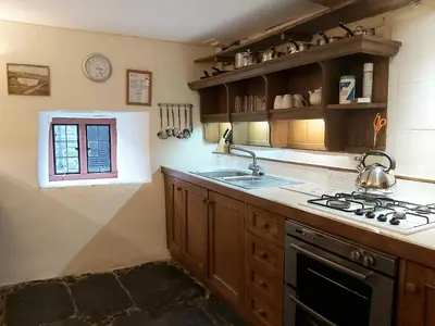 a kitchen with a stove and a sink and a window at Longhouse - Y Beudy in Rhayader