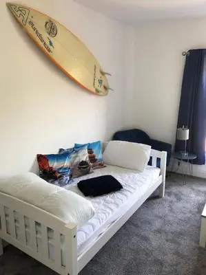 a bed with a surfboard hanging on a wall at Tywyn seaside apartment with Mountain View in Tywyn