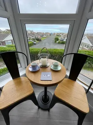 a table and two chairs in a room with a window at Tywyn seaside apartment with Mountain View in Tywyn