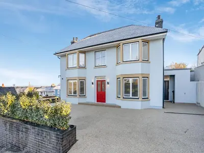 a white house with a red door at Dau Ddeg in New Quay