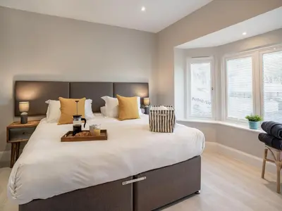 a bedroom with a large bed with a desk and windows at Dau Ddeg in New Quay