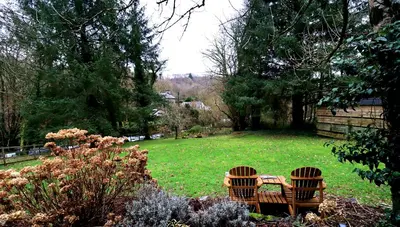two chairs and a table in a garden at Luxurious Riverside Cottage in Snowdonia National Park in Tanygrisiau