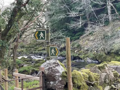 a sign with arrows on it next to a river at Luxurious Riverside Cottage in Snowdonia National Park in Tanygrisiau