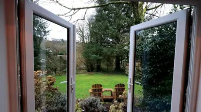 an open door to a garden with a table and chairs at Luxurious Riverside Cottage in Snowdonia National Park in Tanygrisiau