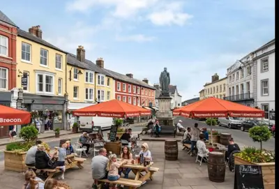 a group of people sitting at tables on a city street at Mountain View Cottage, Hot Tub , Stunning Views in Llanhamlach