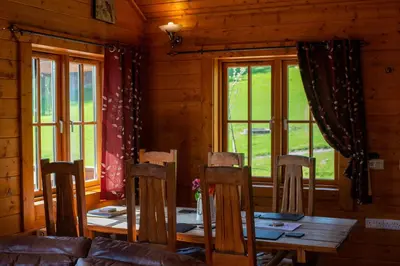 a dining room with a table and chairs and windows at George Cabin - Log Cabin in Wales with Hot tub in Newtown