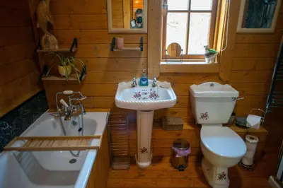 a bathroom with a sink and a toilet and a tub at George Cabin - Log Cabin in Wales with Hot tub in Newtown