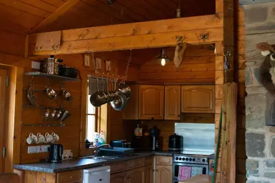 a kitchen with wooden cabinets and a stove at George Cabin - Log Cabin in Wales with Hot tub in Newtown