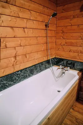 a bath tub with a shower in a wooden wall at Bothy Cabin -Log cabin in wales - with hot tub in Newtown