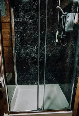 a shower with a glass enclosure in a bathroom at Bothy Cabin -Log cabin in wales - with hot tub in Newtown