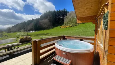 a hot tub on the balcony of a cabin at Bothy Cabin -Log cabin in wales - with hot tub in Newtown