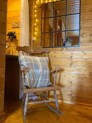 a rocking chair in a room with a wooden wall at Cherry Cabin - Little Log Cabin in Wales in Bettws Cedewain