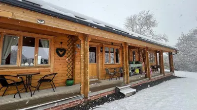 a wooden cabin with a table and chairs in the snow at Cherry Cabin - Little Log Cabin in Wales in Bettws Cedewain