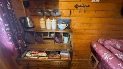 a shelf in a room with a bed and a table at Blossom Cabin - Little log Cabin in Wales in Newtown