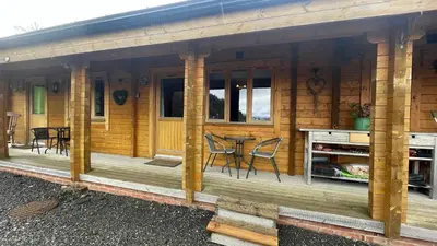 a wooden cabin with a table and chairs on the porch at Blossom Cabin - Little log Cabin in Wales in Newtown