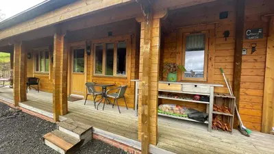 a wooden cabin with a table and chairs on a porch at Blossom Cabin - Little log Cabin in Wales in Newtown