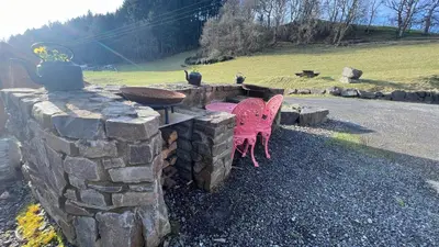 a stone fireplace with two pink chairs next to it at APPLE Cabin - Little Log Cabin in Wales in Newtown