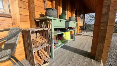a porch of a wooden cabin with a stove at APPLE Cabin - Little Log Cabin in Wales in Newtown