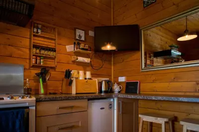 a kitchen with wooden walls and a counter top at APPLE Cabin - Little Log Cabin in Wales in Newtown