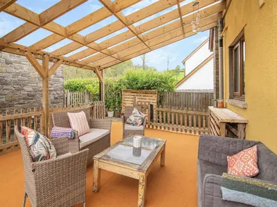 a patio with chairs and a table and a wooden pergola at The Old Nursery in Sennybridge