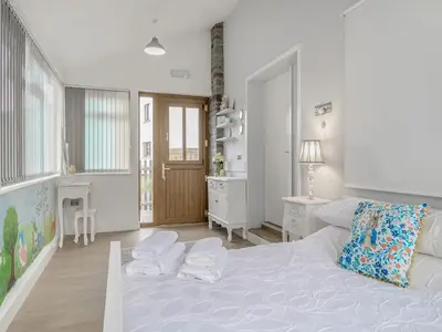 a white bedroom with a large bed and a desk at The Old Nursery in Sennybridge