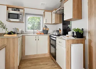 a kitchen with white cabinets and a stove top oven at Ocean Heights Holiday Park in New Quay