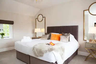 a bedroom with a large bed with white sheets and orange pillows at Marrington Farmhouse in Chirbury