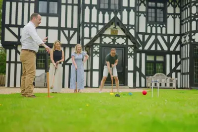 a group of people playing croquet in front of a building at Marrington Hall in Chirbury