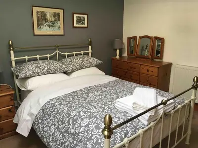 a bedroom with a bed and a dresser and a mirror at Ravens Rest in Llanwrda