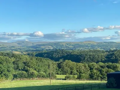 a view of a green field with trees and hills at Ravens Rest in Llanwrda
