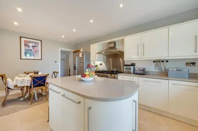 a kitchen with white cabinets and a table with a bowl of fruit at 4 Bed in Brithdir oc-wag722 in Cross Foxes