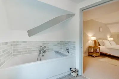 a bathroom with a tub and a bedroom with a bed at 4 Bed in Brithdir oc-wag722 in Cross Foxes