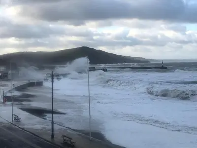 a body of water with waves and a mountain at Stunning Aberystwyth South Beach Apartment in Aberystwyth