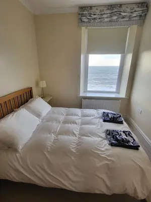 a bedroom with a white bed with a window at Stunning Aberystwyth South Beach Apartment in Aberystwyth