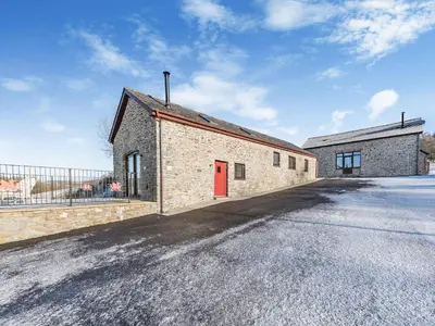 a brick building with a red door on a street at Parlwr Godro - Uk41513 in Llanfair Clydogau