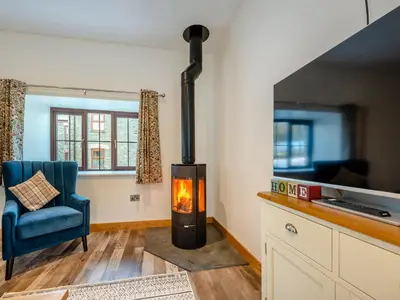 a wood stove in a living room with a blue chair at Ty Gwair - Uk41512 in Lampeter