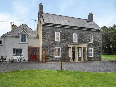 a large stone house with a red door at Brynog Mansion Apartment in Cilcennin