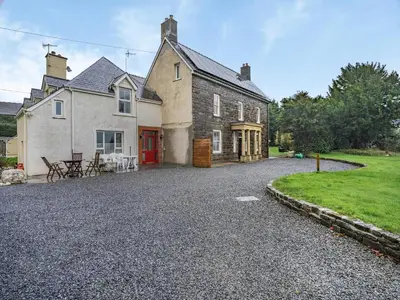 a house with a gravel driveway in front of it at Brynog Mansion Apartment in Cilcennin