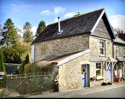 an old stone house with a fence in front of it at Dove Cottage in Newbridge on Wye