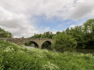 an old stone bridge over a river with trees at The Stokesay in Ludlow