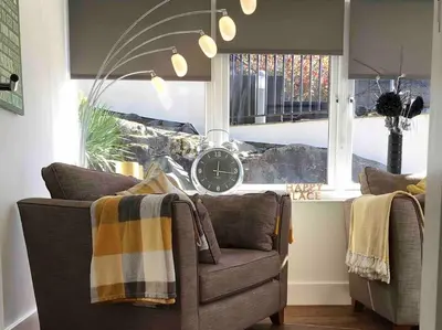 a living room with a couch and a clock in a window at Tre Mynach Barmouth in Barmouth