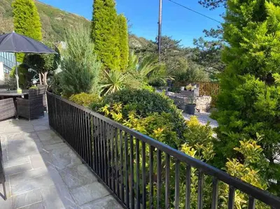a garden with a black fence and some bushes at Tre Mynach Barmouth in Barmouth