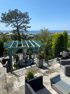 a patio with a blue pergola and chairs at Tre Mynach Barmouth in Barmouth