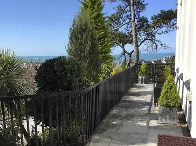 a black fence next to a sidewalk with bushes and trees at Tre Mynach Barmouth in Barmouth