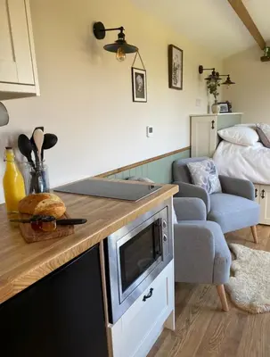 a kitchen with a counter top and a living room at Silver Fern Glamping in Aberystwyth